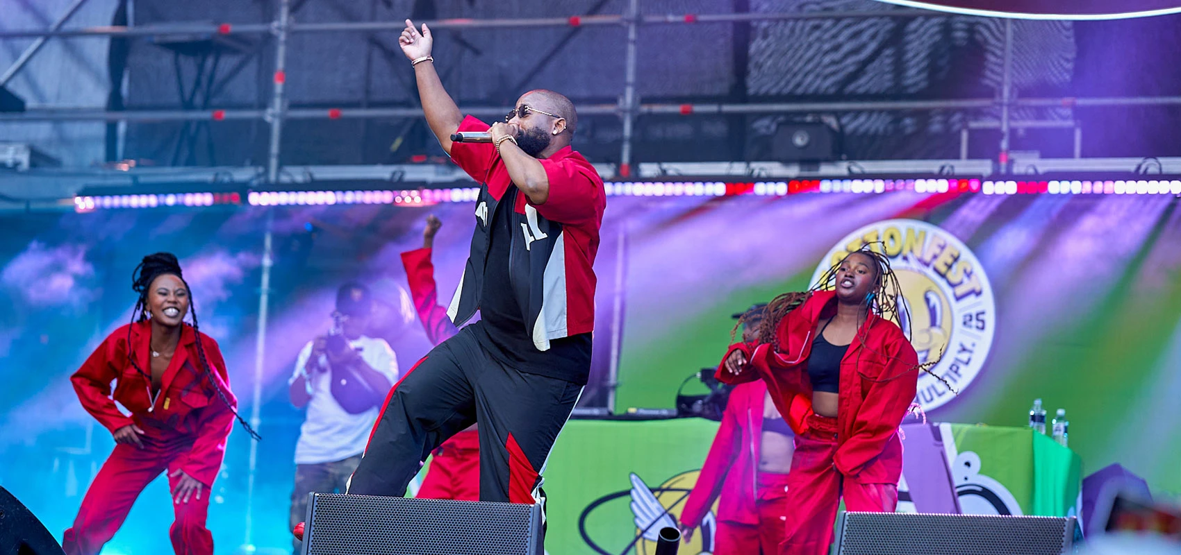 A person singing on stage with backup dancers